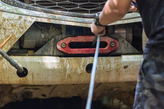 man-use-winch-device-at-front-of-pick-up-off-road-vehicle-e1697482001903