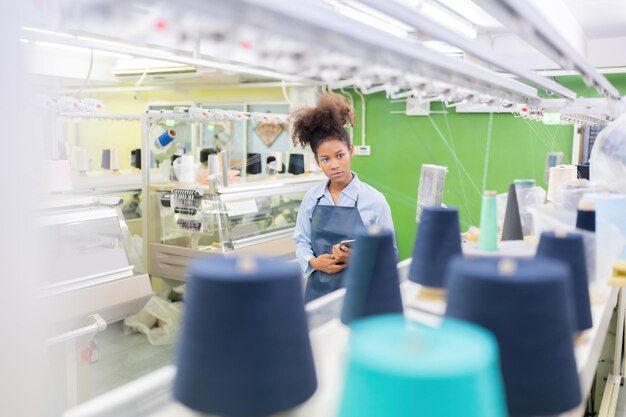 american-female-designer-holding-tablet-walking-around-checking-order-sewing-machine-system-large-weaving-industry-around-there-were-threads-clothing-making-equipment_13