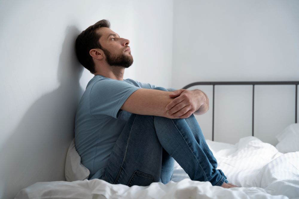 full-shot-anxious-man-sitting-bed